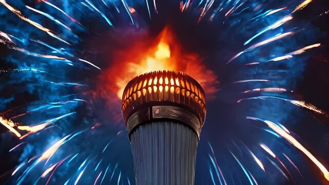 A close-up of an Olympic torch with vibrant flames burning brightly against a backdrop of colorful fireworks at night, ceremony of Paris 2024 Olympics.