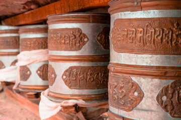 A line of metallic prayer wheels engraved with Tibetan characters