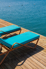 Group of  luxury sun beds on a wooden jetty waiting for tourists in a hot summer day.