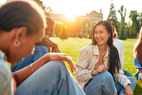 Diverse students relaxing on campus lawn, enjoying friendship, study, and leisure outdoors