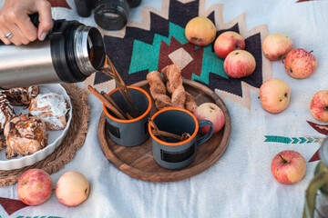 Enjoy a serene outdoor picnic with pastries and apples laid out on a chic blanket in a cozy setting. Vertical