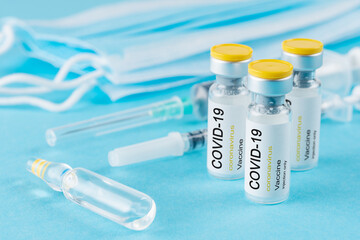 Coronavirus vaccine vial glass with a syringe on blue background. Covid-19 medicine vaccination concept. World pandemic concept.