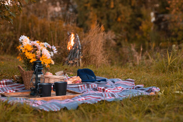 romantic fall picnic with flowers, lanterns for a cozy date in a serene natural setting outdoor at...