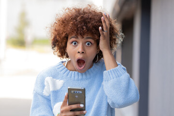 girl with mobile phone in the street and expression of surprise