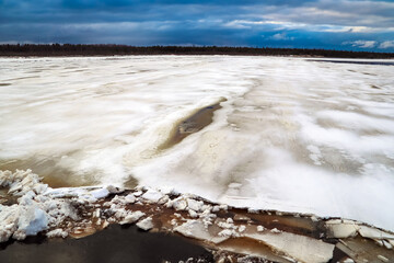 Spring flood, river with remnants of ice, melting ice, landscape river ice spring, thawed dangerous ice.