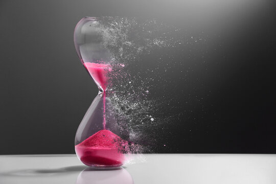 Hourglass dissolving on table against dark background. Fleeting time