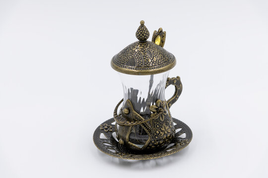 Close-up side view of empty armudu (armuda, bogmaly) - traditional metal and glass tea or coffee cup with small spoon from Turkey or Azerbaijan on white background. Souvenir from travel theme.