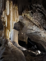 Stalactites and Stalagmites in Amatérská Cave, Moravian Karst, Czech Republic. Stunning underground formations reflecting in a calm pool, showcasing natural beauty and geological wonders.