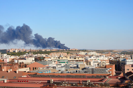 Black smoke from a fire in the distance behind residential buildings in the city of Madrid, Spain