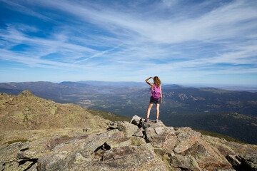 Obraz premium Mountaineer trekking woman with on the top of Peñalara peak, the highest mountain in Madrid, looking towards the horizon. In the Guadarrama National Park, Spain