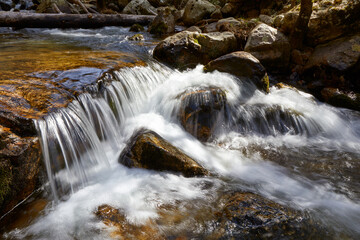 Water falling on rocks in a small river waterfall with a silk effect due to long exposure
