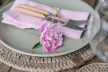 Table setting with light green ceramic plates and pink peonies
