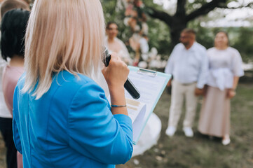 Young woman, professional leading journalist with a microphone and a piece of paper gives a speech,...