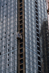 Close-up side view of blue glass wall of modern skyscraper building under construction. Copy space. Abstract construction background. Housing development theme.