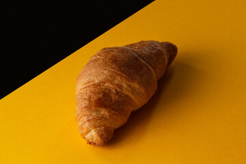 Croissant on a yellow and black background. Delicious pastries on a yellow-black background