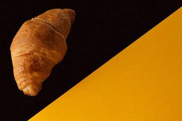 Croissant on a yellow and black background. Delicious pastries on a yellow-black background