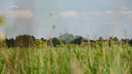 Scenic landscape view over wetlands lake with reeds with The Tor in Glastonbury in the distance on Somerset Levels, England UK © Travelanza