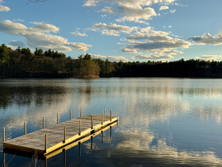 Pond life - A small boat dock reaches out into a quiet tree-lined pond in rural New England.