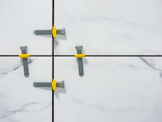 tile leveling system, laying white marble effect porcelain tiles on the wall