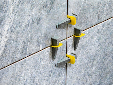 tile leveling system, laying gray marble effect porcelain tiles on the wall