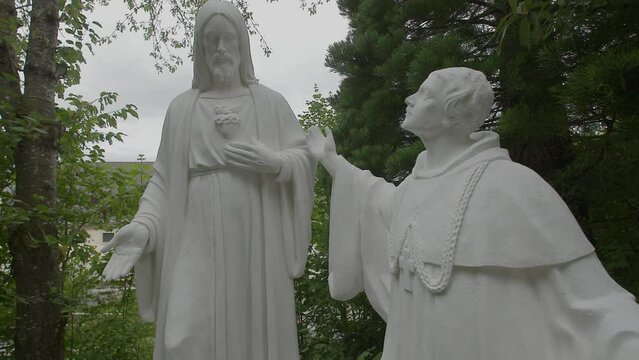 white stone statues of Jesus and catholic abbot
