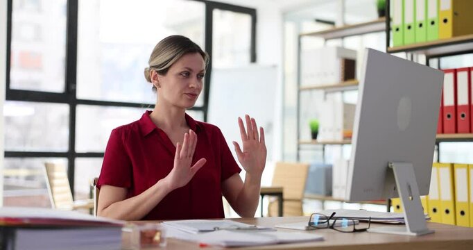 Woman worker has online conversation using computer and shows refusal sign at workplace. Employee waves hands away and refuses offer slow motion