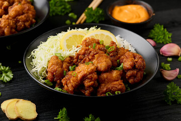 Japanese Fried crispy Chicken Karaage in black bowl with rice and cabbage