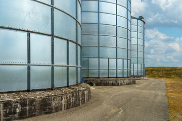 silver silos on agro manufacturing plant for processing drying cleaning and storage of agricultural products, flour, cereals and grain. Large iron barrels of grain. Granary elevator © Pokoman