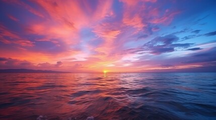 Fototapeta premium A breathtaking sunset scene over calm ocean waters with dramatic colors ranging from pink to deep blue, highlighting the beauty and serenity of nature's evening show.
