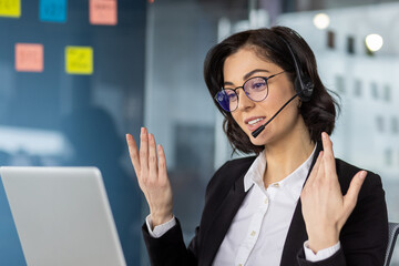 Confident businesswoman wearing a headset and suit, conducting an online meeting with expressive...