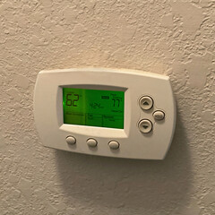 House wall HVAC thermostat air conditioning digital control panel.