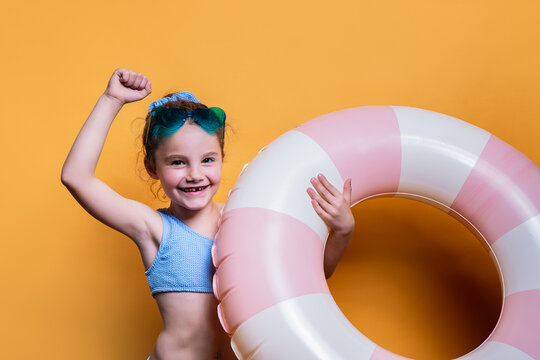 Smiling girl with swim ring on a yellow background