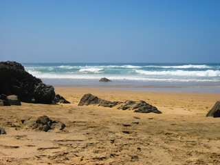 A sandy beach with rocks and ocean in the background