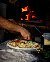 manos poniendo queso a las pizzas