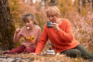Family picnic in park on happy autumn weekend with smile. Grandma with girl children relax, celebrate outdoor fun and quality time together .