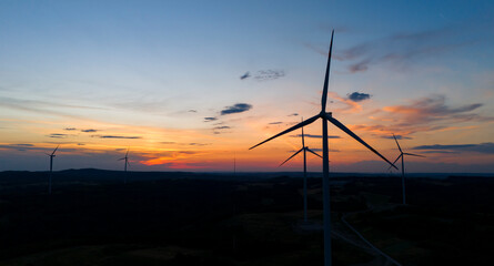 Obraz premium wind turbine in the countryside in the time of sunset background. Wind Turbines at Sunset. Aerial view of a wind farm at sunset.