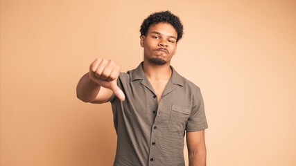 Sad man making thumbs down sign and shaking head in displeasure