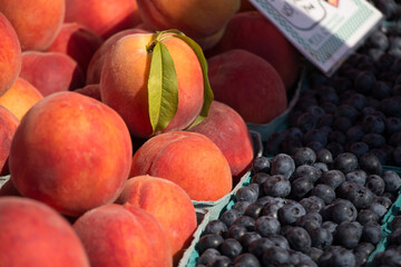Peaches, one with a leaf, and blueberries at the farmers market