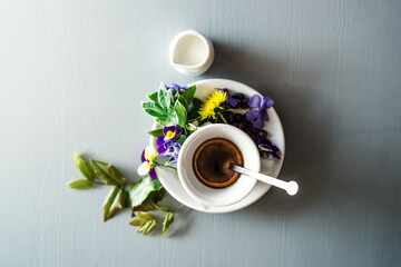 Cup with hot espresso, with pansy flower on top.