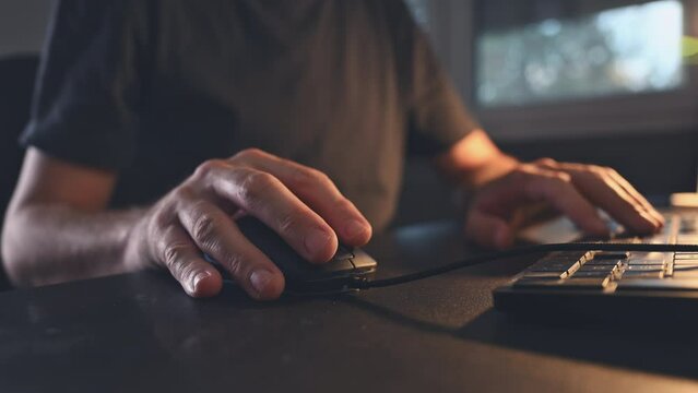 Closeup of male hands using computer mouse at home office desk, freelancer working from home