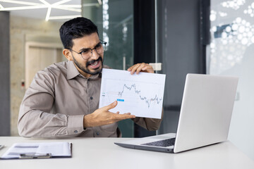 Fototapeta premium Frustrated businessman showing financial report during online meeting