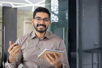 Smiling businessman holding notepad and pen in office during presentation