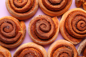 Tasty cinnamon rolls on lilac background