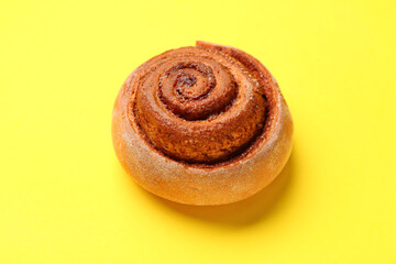 Tasty cinnamon roll on yellow background