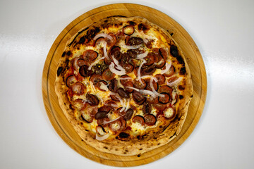 Calabrian sausage pizza served on a round board and set table