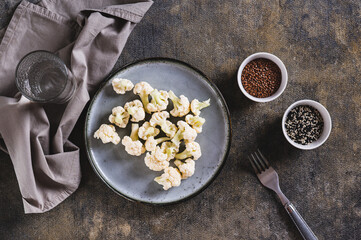 Pieces of raw cauliflower for diet on a plate on the table top view