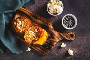 Keto burgers on cauliflower fritters with cutlet, tomato and cheese on a board top view