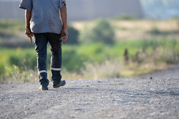 A man walking down a rural gravel road, with a scenic countryside backdrop, highlighting solitude...