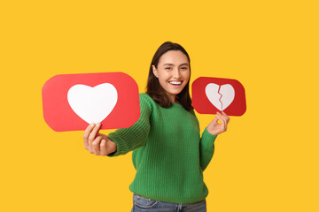 Beautiful young happy woman with heart like and dislike icons on yellow background