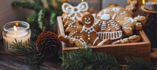 Banner. Wooden box with homemade delicious gingerbread cookies decorated with white icing. Handmade zero waste gift for Christmas or New Year. Cozy home atmosphere, fairy lights, fir tree branches